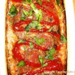 Homemade meatloaf topped with a drizzle of ketchup and chopped parsley.