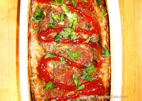 Homemade meatloaf topped with a drizzle of ketchup and chopped parsley.